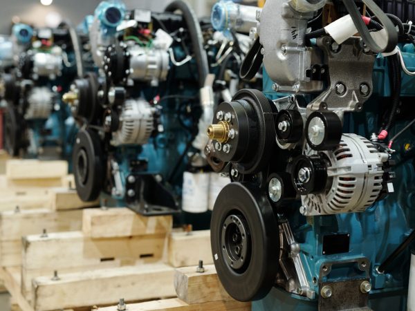 Row of motors of huge industrial machines with rotating shafts inside distribution warehouse of large contemporary plant
